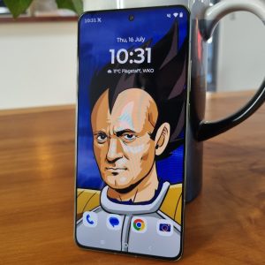 Moto Edge 70 review of wallpaper featuring a stylized Vegeta-inspired character, standing upright on a wooden table in front of a black mug.