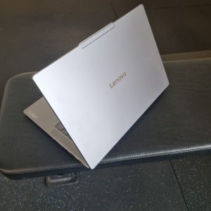 Back of the Lenovo Yoga Pro 7i Aura Edition Gen 10 with the "YOGA" detail showing while it sits on a bench